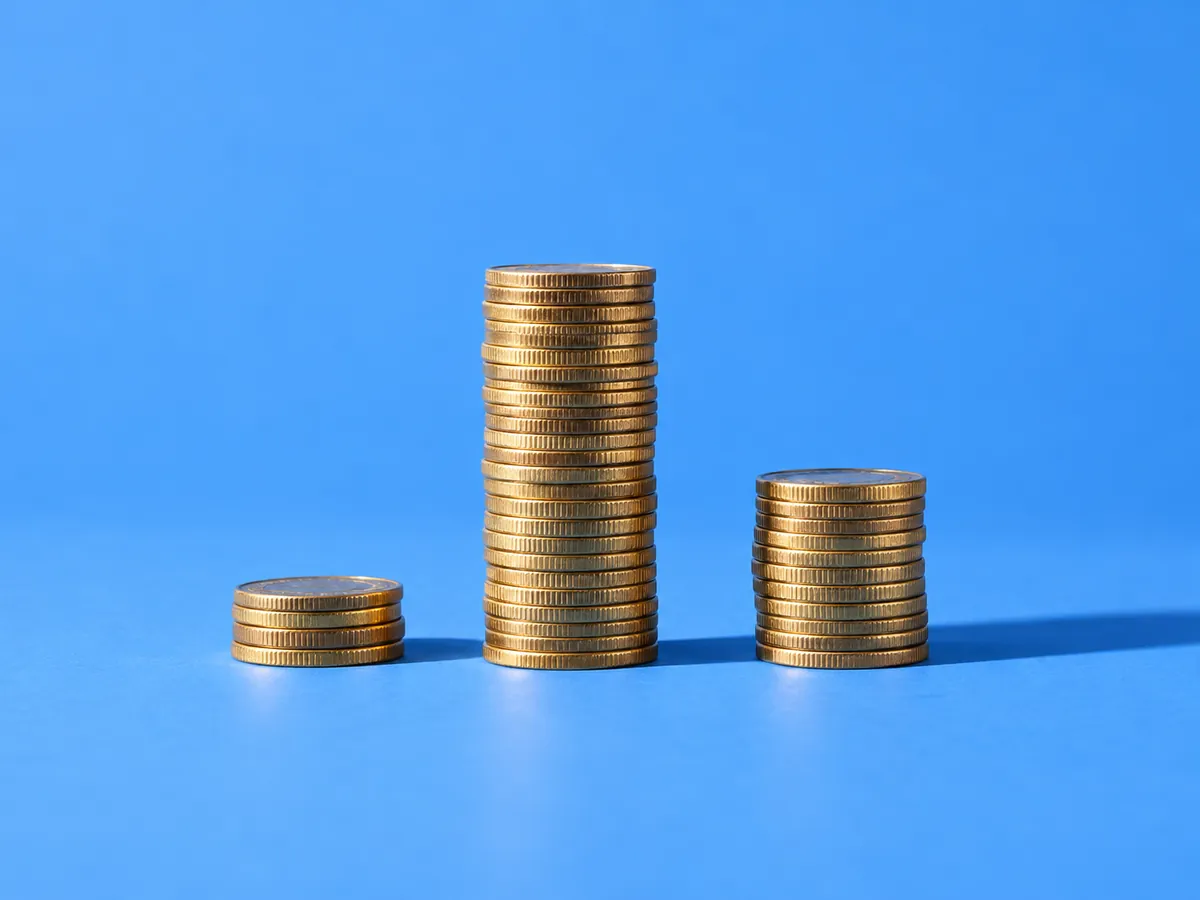Three coin stacks of different heights in a row, representing how the real costs of SEO tools, agencies and automation compar