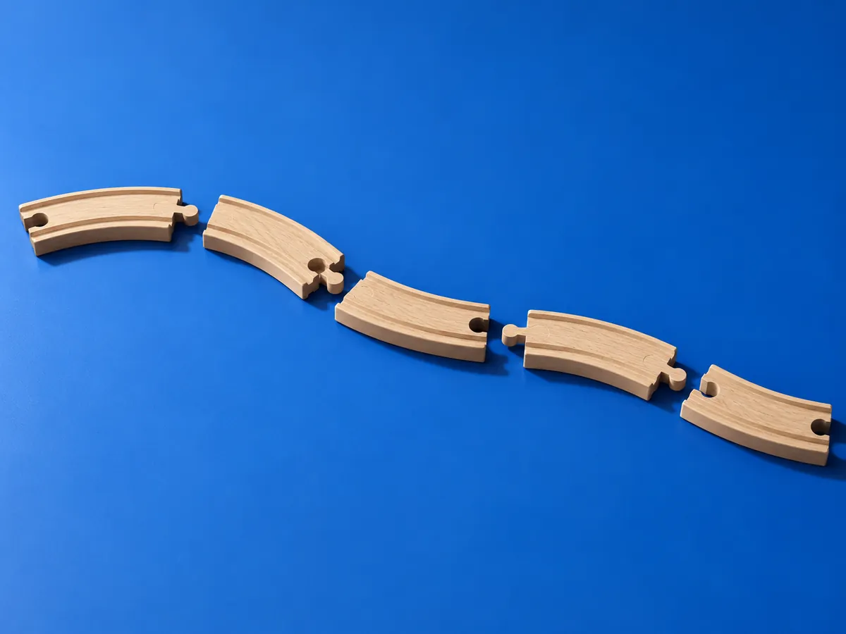 Toy train track pieces laid out but not joined, symbolizing disconnected schema nodes that machines cannot parse as one graph